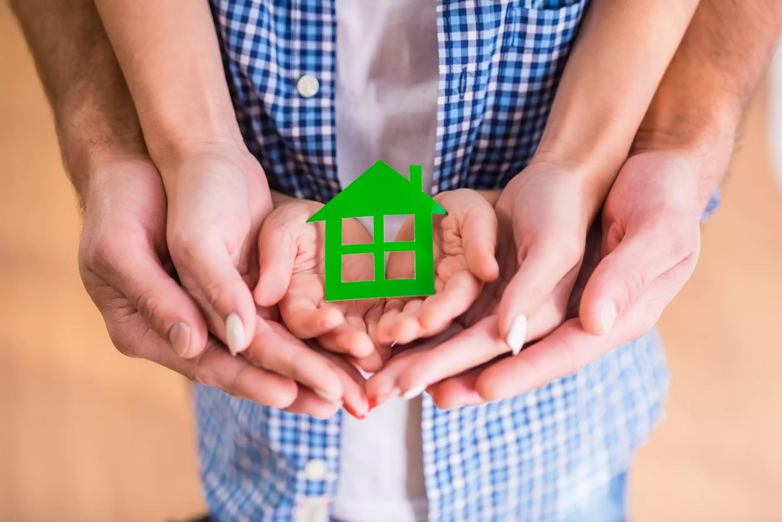 A family holding a green house shaped cutout